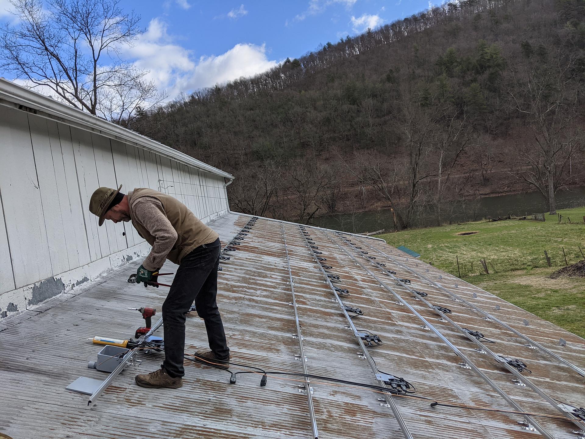 Man installing solar panel brackets on roof